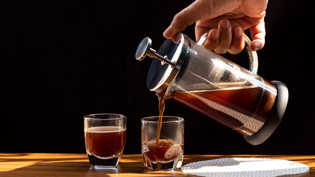 Homme préparant son café avec une cafetière à piston en cuisine