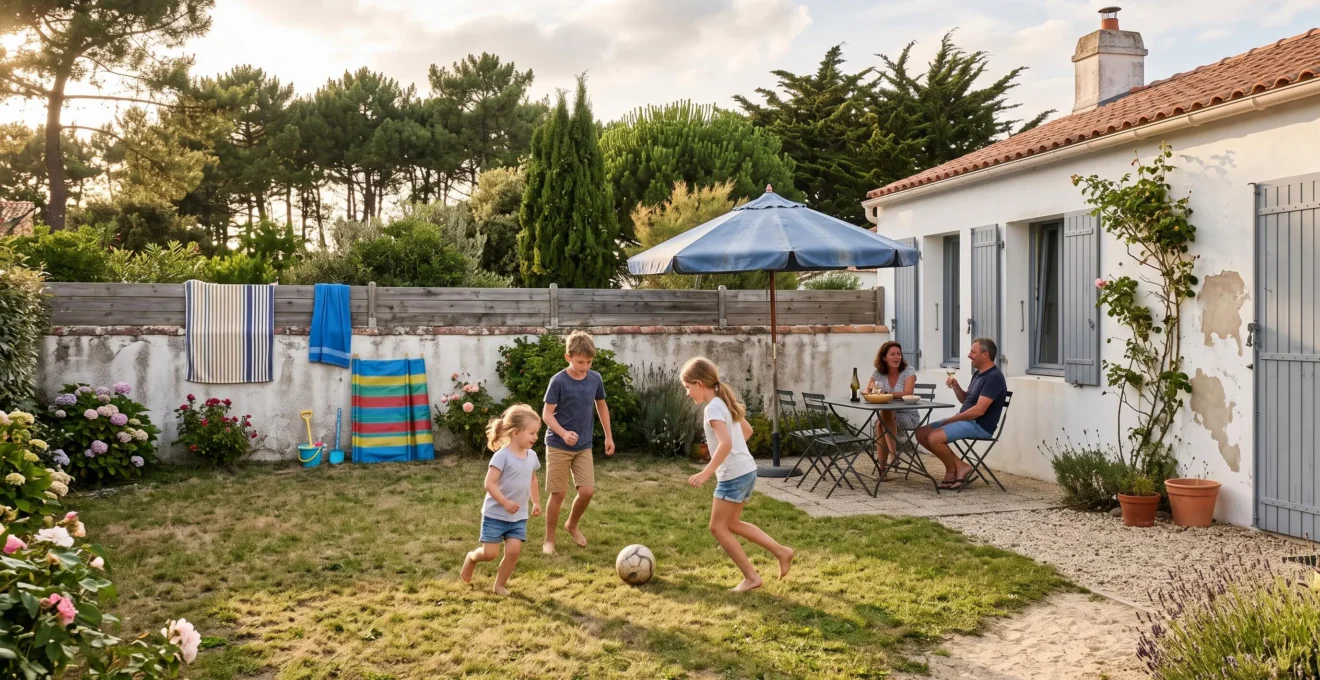 Des enfants jouent au ballon dans le jardin d'une maison de vacances tandis que des adultes sont attablés sous un parasol en Vendée.